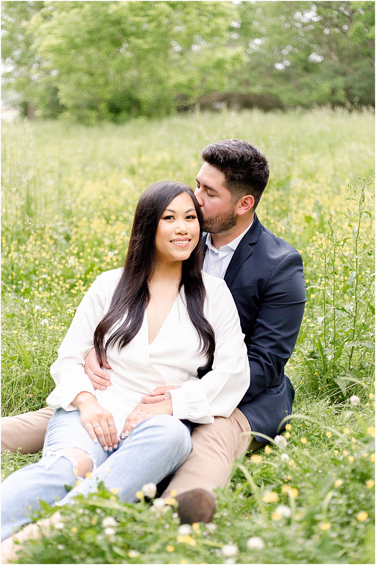 Man hissing a woman's hair in a field picture taken by Engagement Photographer