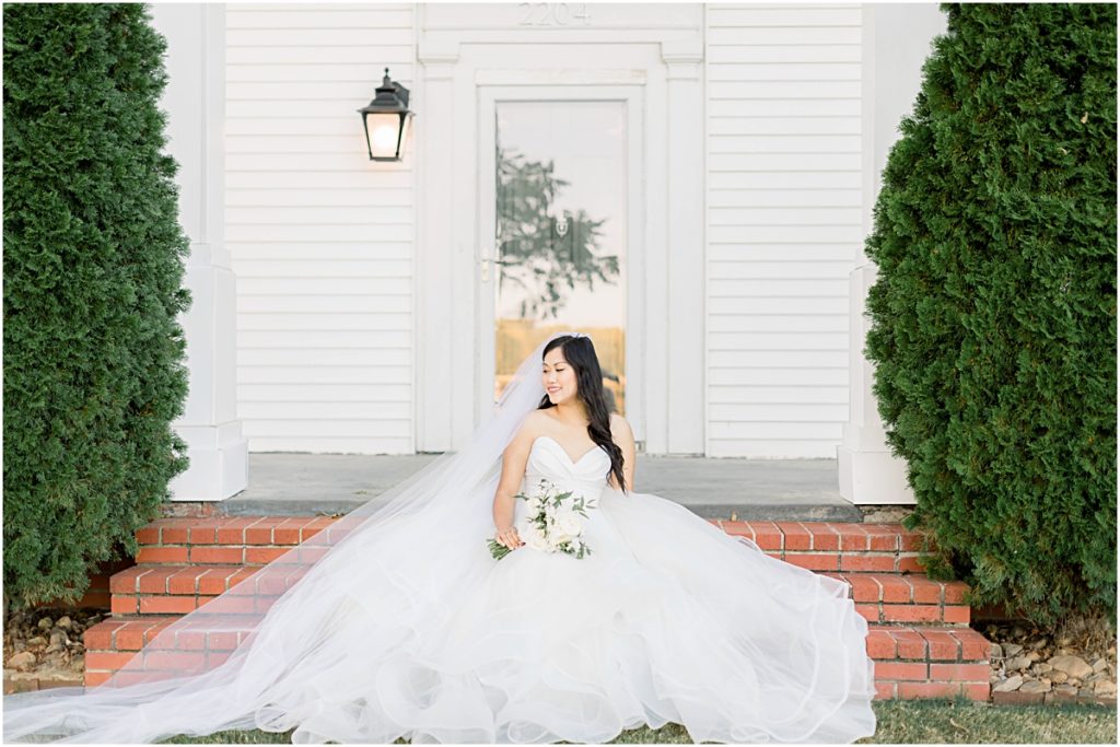 Carina sitting and smiling on steps outside wedding venue