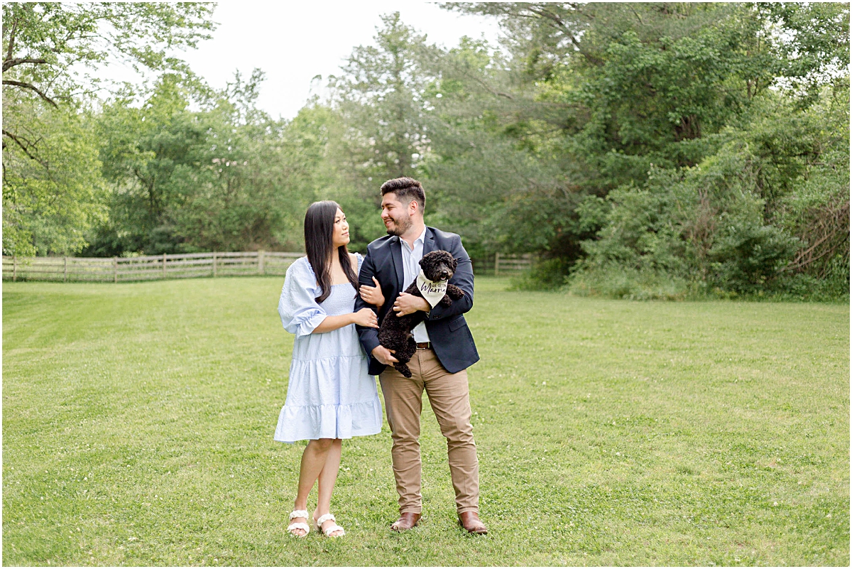Couple holding their dog in a field during Engagement Photography Session