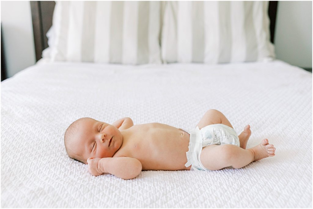 Baby James in a diaper on a bed during Newborn Photography session