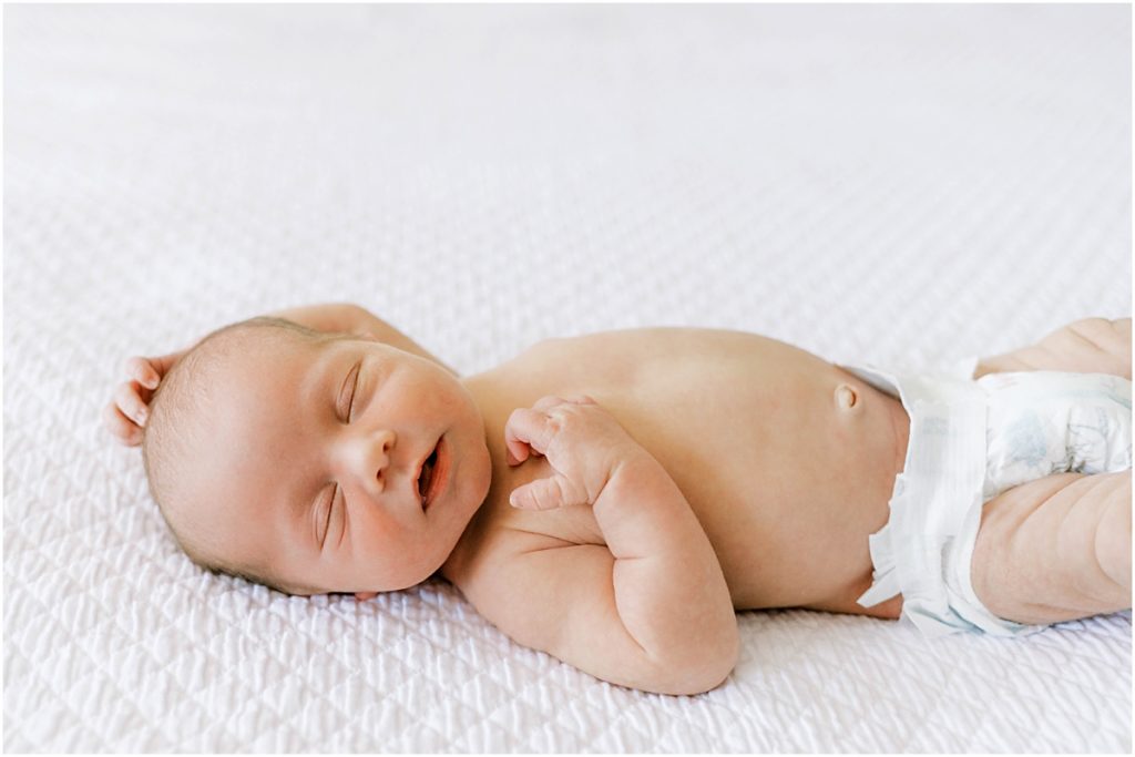 Baby James in diaper on a bed during Newborn Photography session