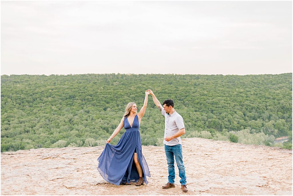 Jarod spinning Sarah around in a flowing gown during their engagement session at Devil's Den State Park.