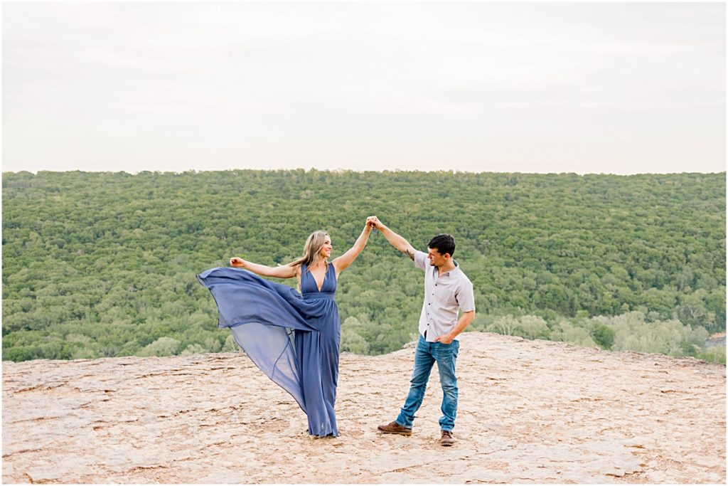 Sarah spinning and throwing her dress skirt while Jarod admires her beauty during their engagement session in Fayetteville, Arkansas.