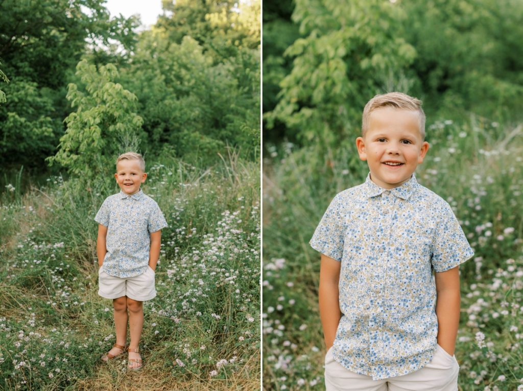 Little boy standing and smiling in a flower field.