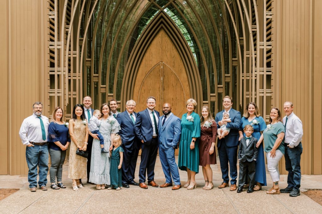 Photo of the grooms with both sides of their family standing in front of Cooper Chapel in Arkansas.