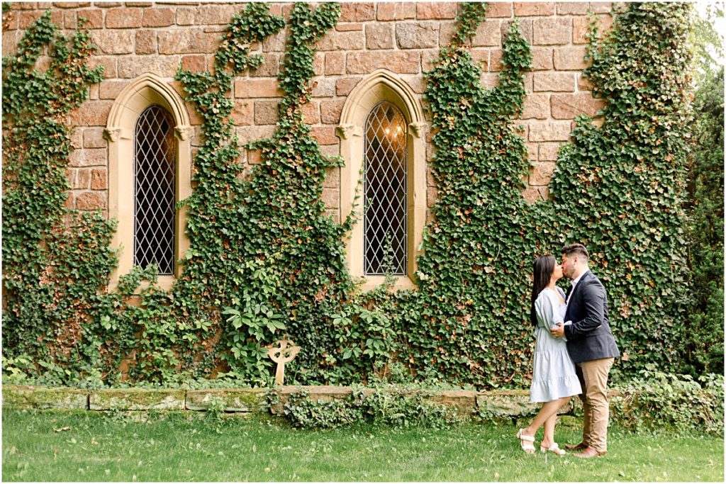 Jorge and Carina kissing in front of St. Catherine's vines and windows during Fayetteville Engagement Session