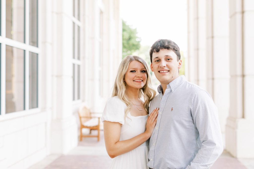Couple standing close and smiling during their engagement session at University of Arkansas.