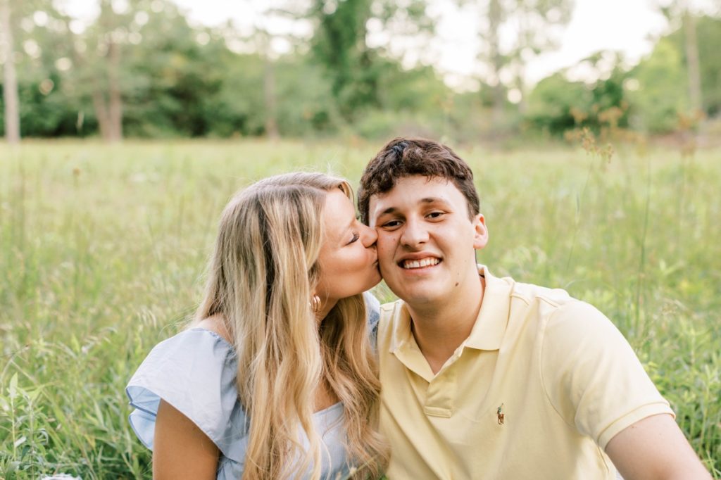 A woman kissing her fiance on the cheek during their engagement session.