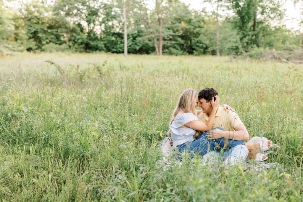A couple sitting in the grass at Wilson Springs Nature Reserve with their foreheads pressed together during an intimate moment.