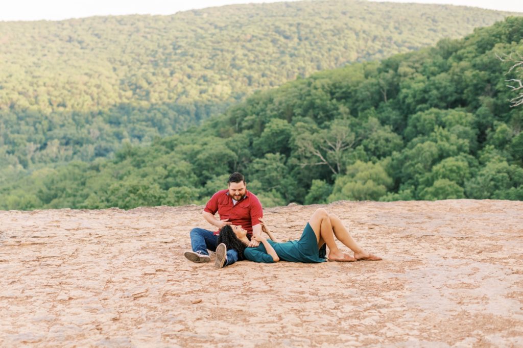 Tommy and Leah laying on a cliff at Yellow Rock smiling at each other during their engagement session.