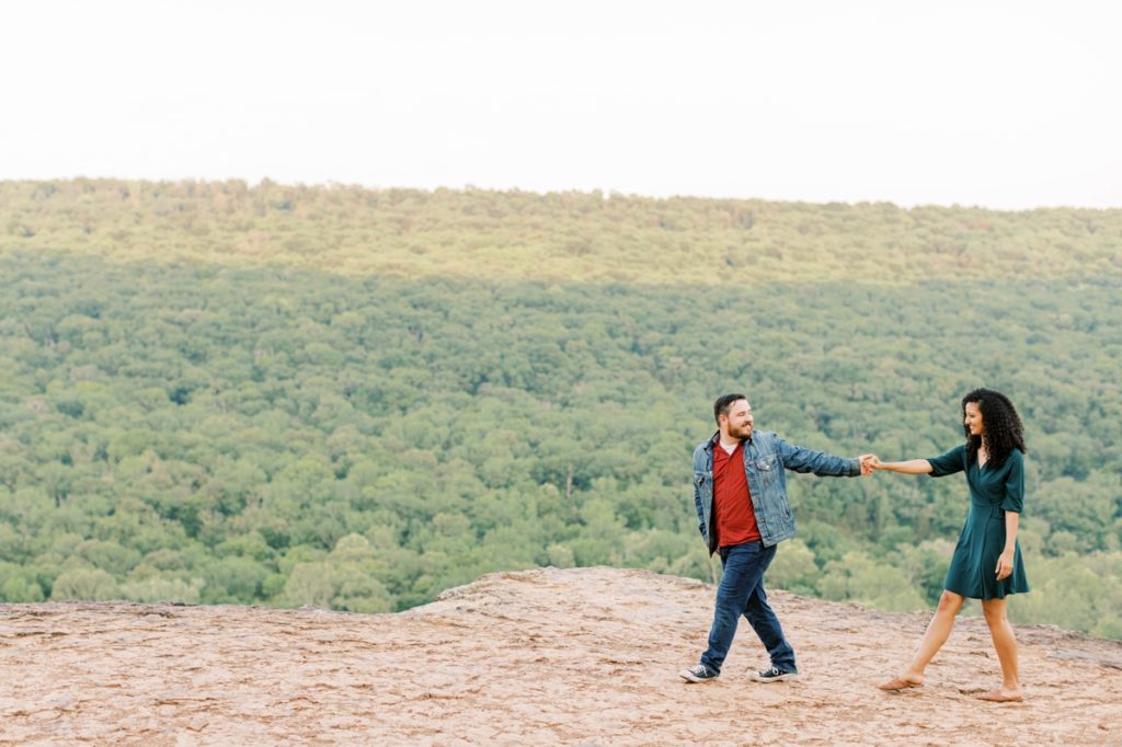 Tommy leading Leah across a cliff at Yellow Rock in Arkansas during their engagement session.
