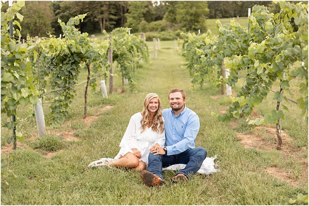 Jackson and Remington sitting on the grass between the vineyard rows during a Springdale AR Engagement session 