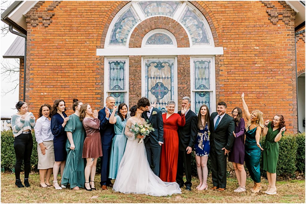 Full family picture outside church with Emily and Lawrence kissing during Arkansas Elopement 