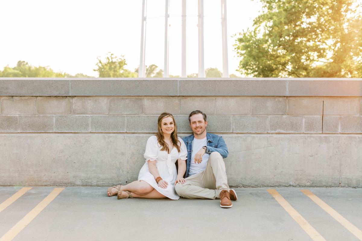 Couple sitting on top of a parking garage in Bentonville, AK during their engagement session