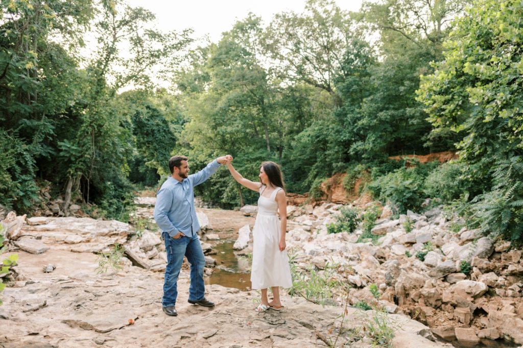 A man spins his fiance on a rock during their engagement session