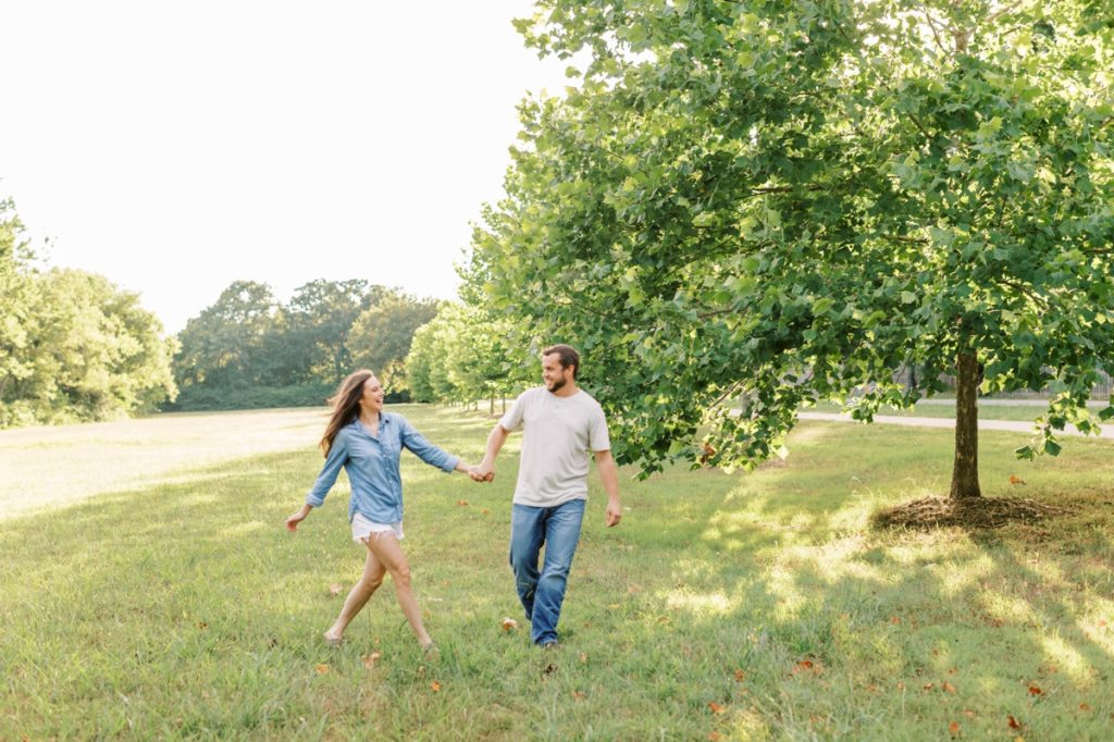 Couple running and laughing through a field at Lake Fayetteville