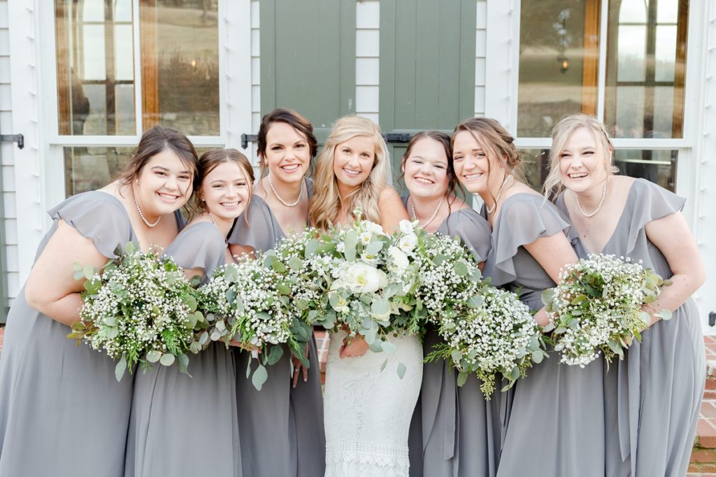 A bride and her bridesmaids smiling with their green and white bouquets from Carey's Flowers.