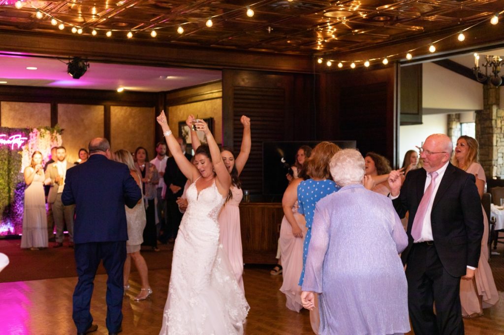 The bride and her wedding guests throwing their hands in the air and partying during her wedding reception
