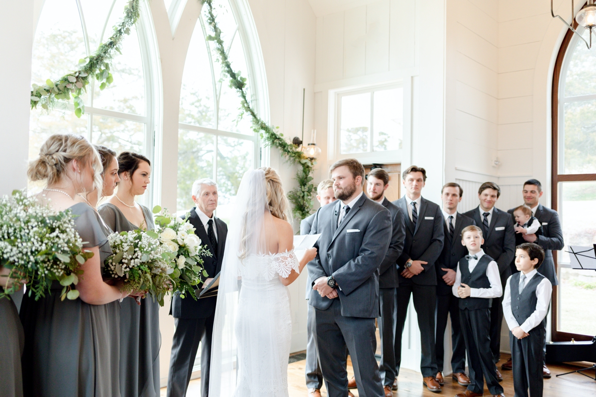 A couple standing at the altar with their groomsmen and bridesmaids on their wedding day