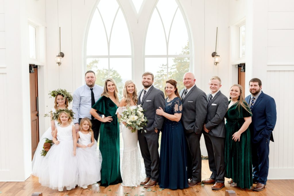 A bride and groom smiling with their family that incorporates little kids into their wedding.