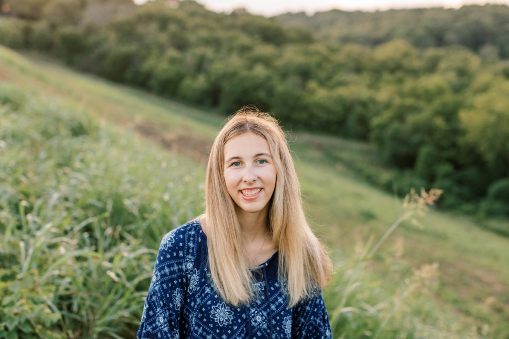 Natalie smiling in a field during her high school senior session.