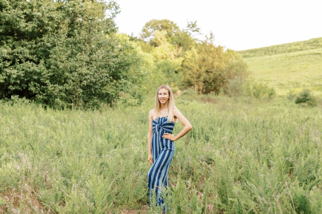 Natalie smiling in a field during her high school senior session.