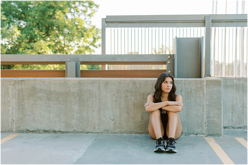 Madison sitting against a low wall; photograph taken by a Senior Photographer in Bentonville AR